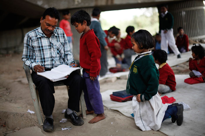 4. Дети в возрасте от 4 до 14 лет изучают основы чтения. Некоторым учитель объясняет теорему Пифагора. На фото основатель школы Раджеш Кумар проверяет сочинение на свободную тему. 