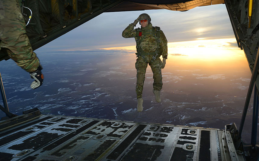 10. Американский военный отдает честь во время прыжка с самолета С-130 Hercules.