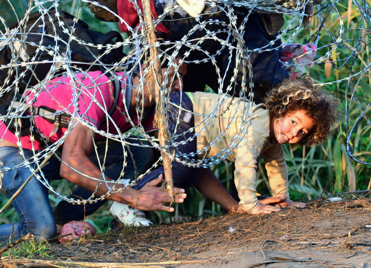 13. Семья мигрантов проползает под проволокой возле села Röszke на венгерско-сербской границе. Фото: ATTILA KISBENEDEK.