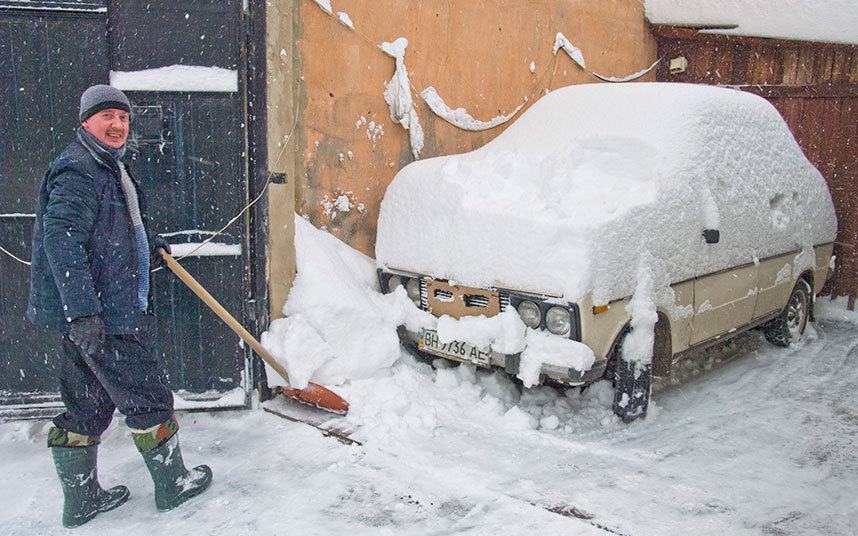 7. Житель Одессы очищает от снега свой автомобиль, после сильнейшего снегопада.