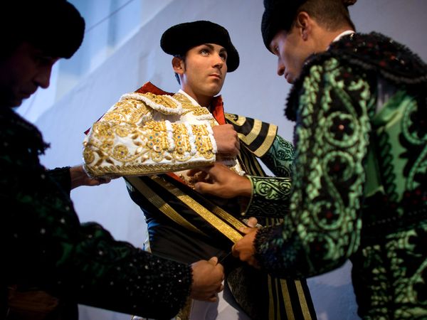 5. Помощники подгоняют одежду испанского матадора Серафина Марина перед боем в Памплоне в 2008 году. Костюм матадора является одной из самых узнаваемых традиционных нарядов Испании.