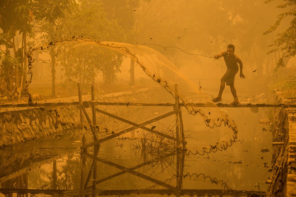10. Бьорн Ваугн. Рыбак в Индонезии ловит рыбу в загрязненном канале. 