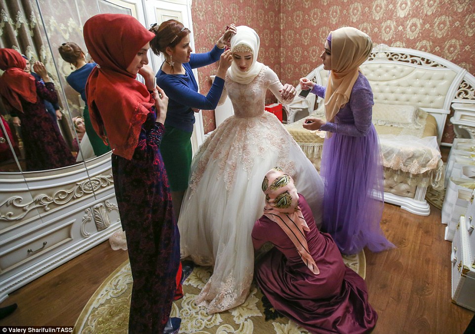 3. Подруги невесты также одеты в традиционные чеченские платья. Девушки поправляют наряд невесты, чтобы все было идеально.