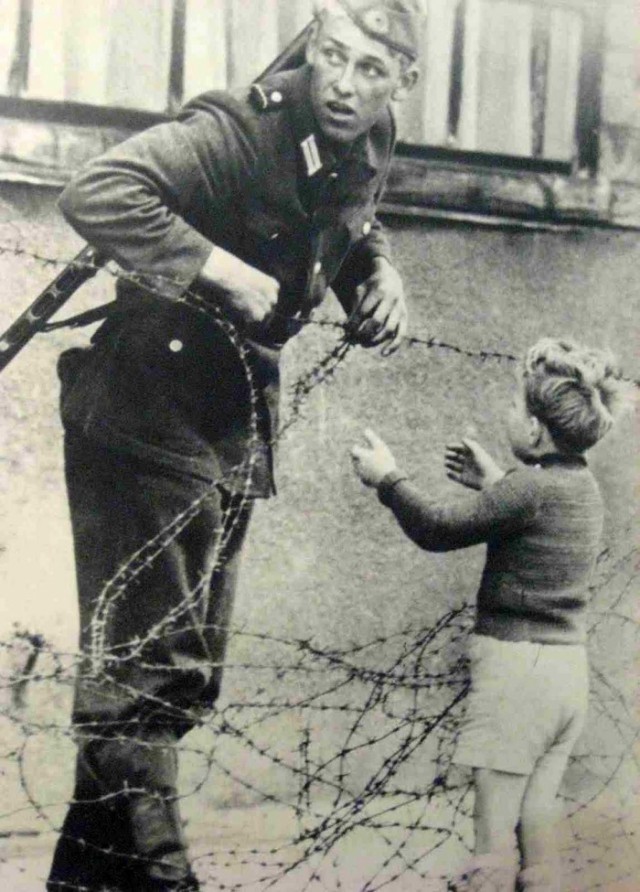 3. Солдат помогает мальчику пересечь Берлинскую стену.