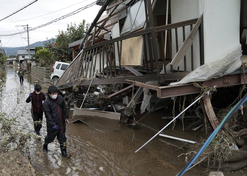10 . Жители, идущие по территории, пострадавшей от тайфуна.