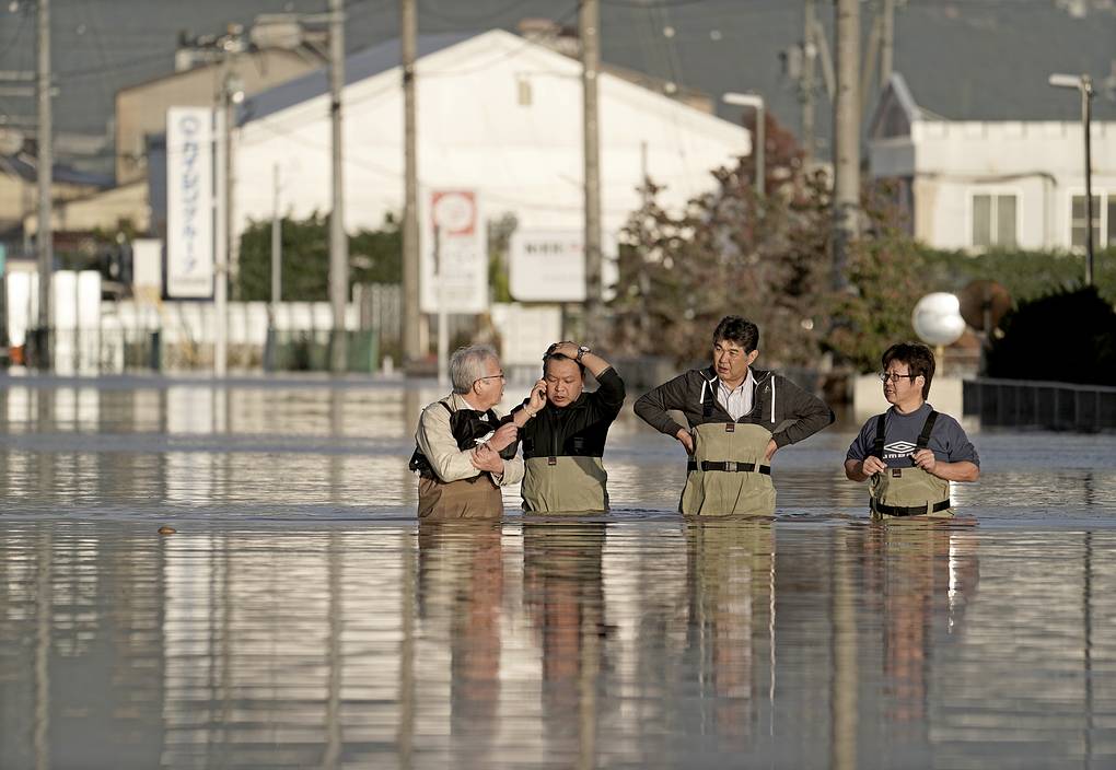 2. Рабочие, стоящие в паводковой воде после прохождения тайфуна Хаджибис в Нагано.