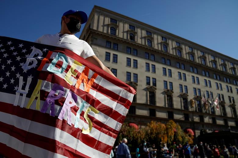 6. Мужчина машет американским флагом с надписью «Байден Харрис» возле Белого дома в Вашингтоне.
